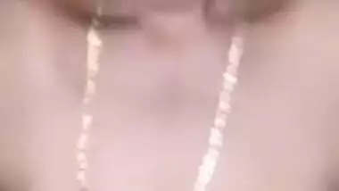 Indian aunty with saggy body stands against the wall posing on camera